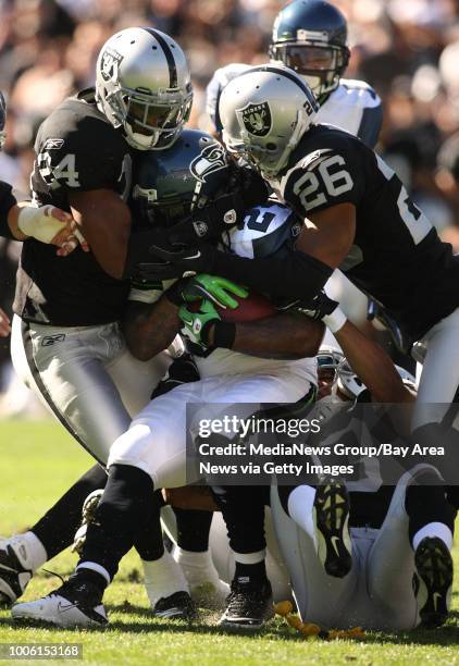 Seattle Seahawks running back Marshawn Lynch, center, is bottled up by Oakland Raiders defenders Michael Huff , Tyvon Branch and Stanford Routt in...