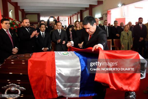 Paraguayan President Horacio Cartes places a flag of the ruling National Republican Association Colorado Party over a national flag over the coffin...