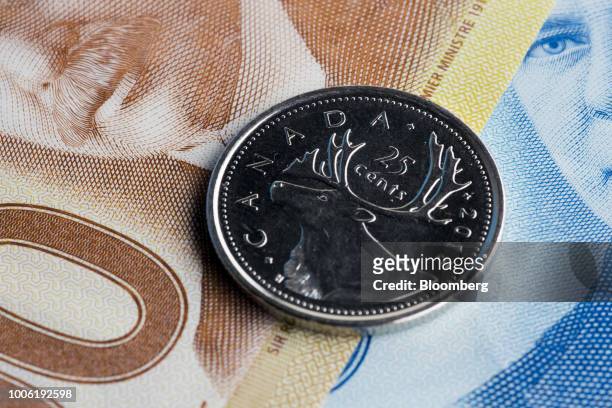 Canadian twenty-five cent coin and banknotes are arranged for a photograph in Toronto, Ontario, Canada, on Wednesday, July 25, 2018. One of Prime...