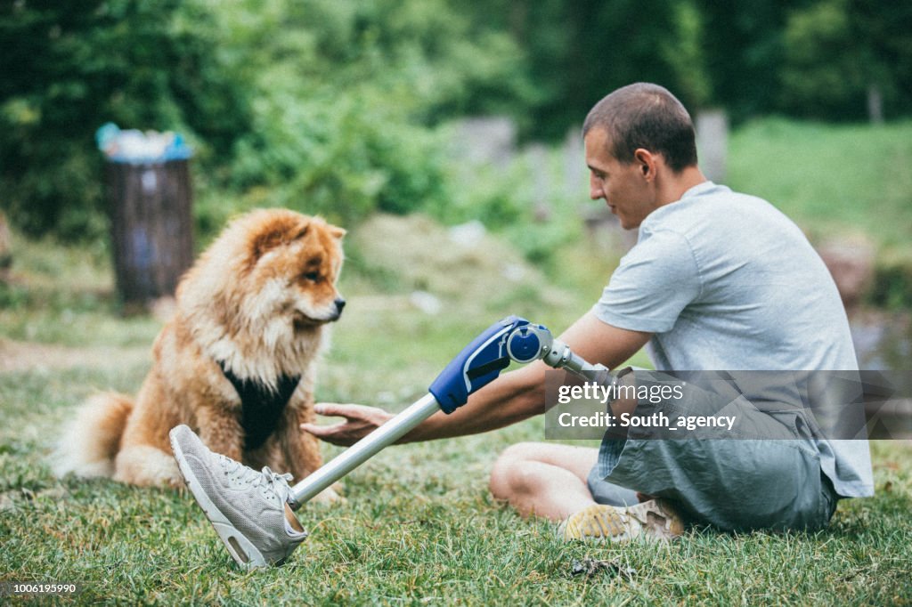 Disability man with prosthetic leg sitting with his dog