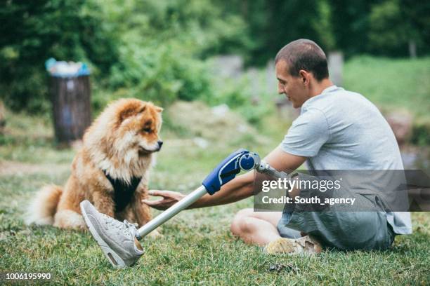 disability man with prosthetic leg sitting with his dog - animal leg imagens e fotografias de stock