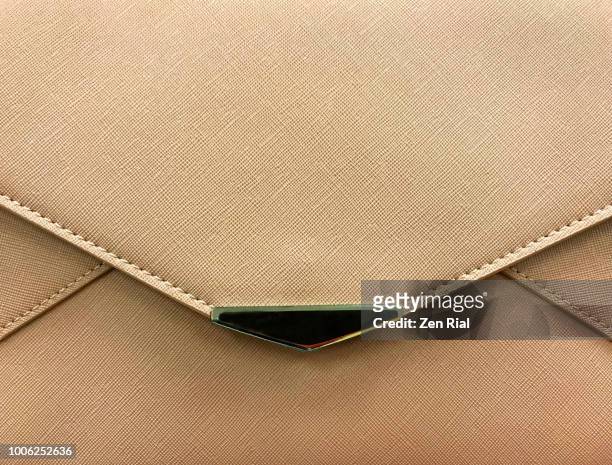 front view of a light brown purse showing edge of flap and metal decor - bolso dorado fotografías e imágenes de stock