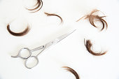 Lock of hair and a haircut scissor in a white background