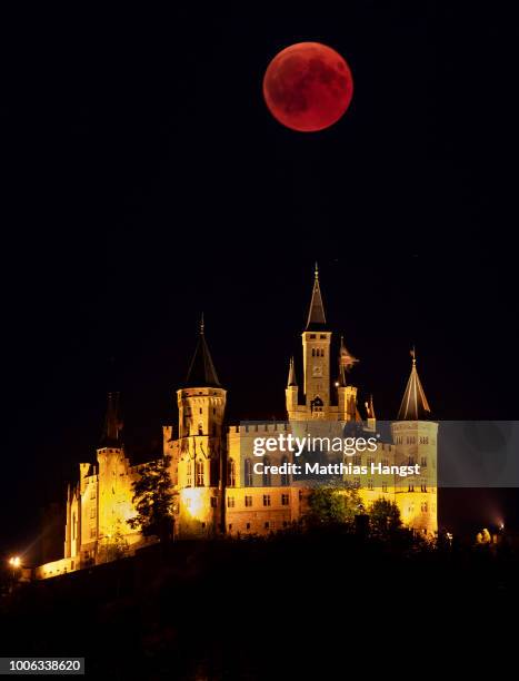 Blood Moon rises behind The Hohenzollern Castle, the ancestral seat of the Prussian Royal House and of the Hohenzollern Princes, situated at the...