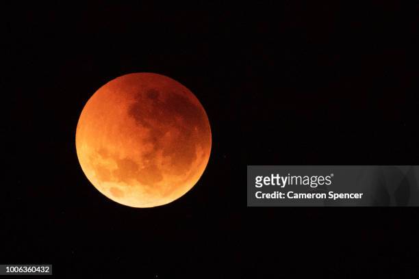 The moon is seen turning red over the Sydney skyline during a total lunar eclipse on July 28, 2018 in Sydney, Australia. The lunar eclipse was the...