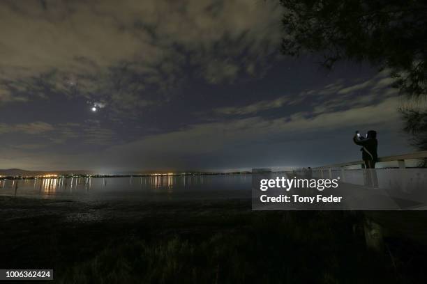 People watch the Lunar eclipse over Tuggerah Lake on the Central Coast of NSW on July 28, 2018 in Sydney, Australia. During this eclipse, when...