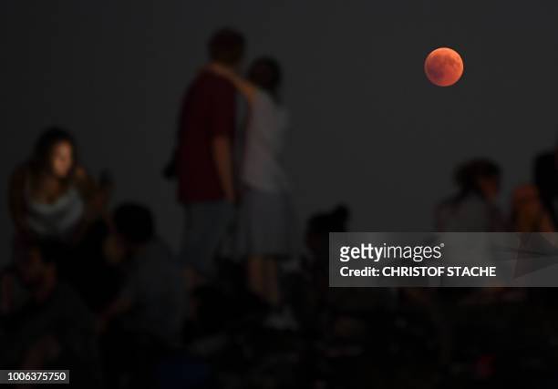 People watch the total lunar eclipse in the Olympic park in Munich, southern Germany, on July 27, 2018. The longest "blood moon" eclipse this century...