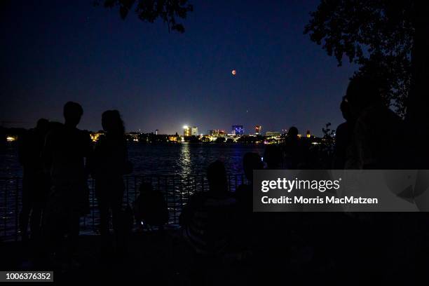 People gather at the Alster Lake to watch the 'blood moon' eclipse over the northern German city of Hamburg on July 27, 2018. During this eclipse,...