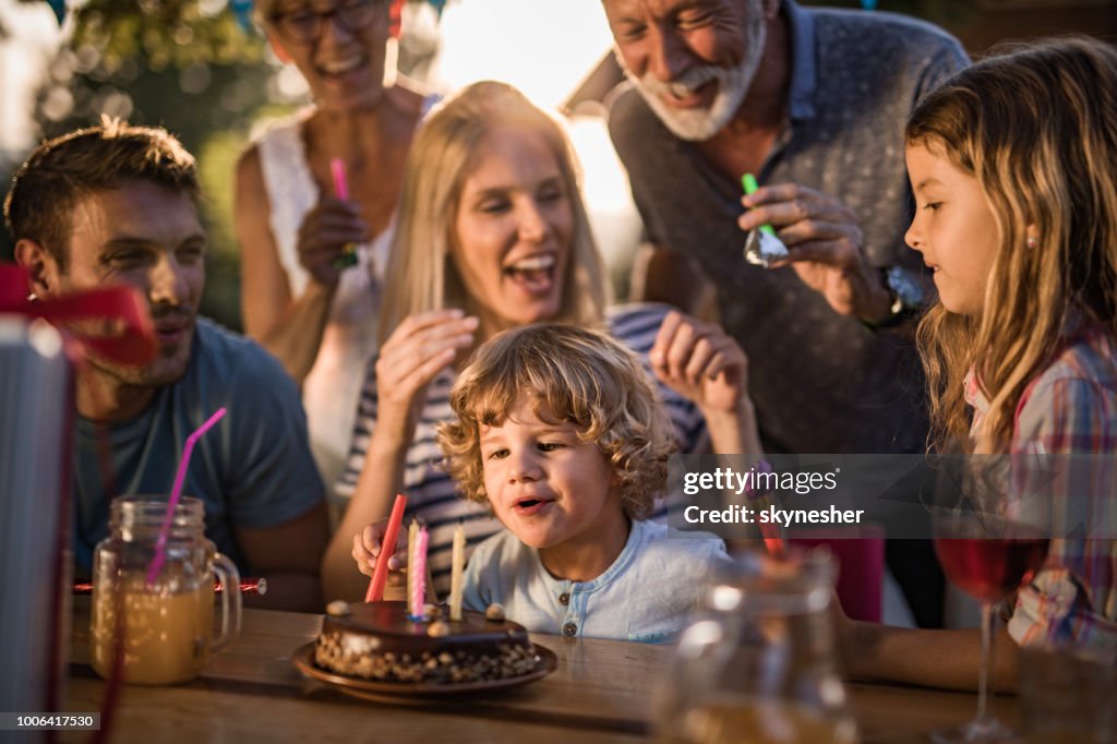 Família de várias gerações feliz comemorando o aniversário do filho ao ar livre.