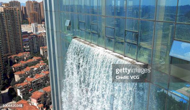 An artificial waterfall comes down from a 121-meter-tall office building on July 20, 2018 in Guiyang, Guizhou Province of China.