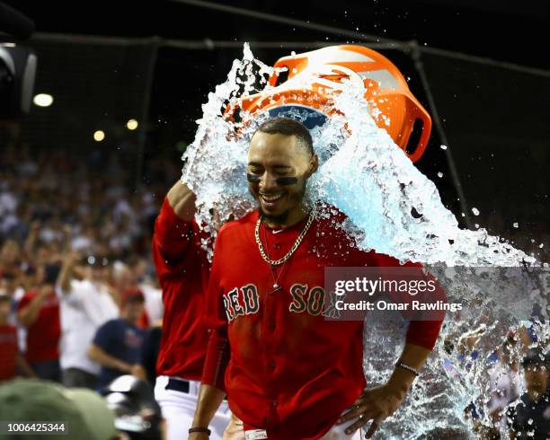 Mookie Betts of the Boston Red Sox recieves a Gatorade bath from J.D. Martinez of the Boston Red Sox after hitting a walk off home in the bottom of...