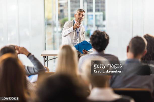mid volwassen arts onderwijzen op een seminarie in een bestuurskamer. - gezondheidszorg en medicijnen stockfoto's en -beelden