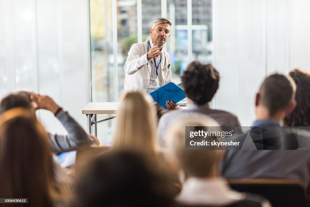 Mid adult doctor teaching on a seminar in a board room.