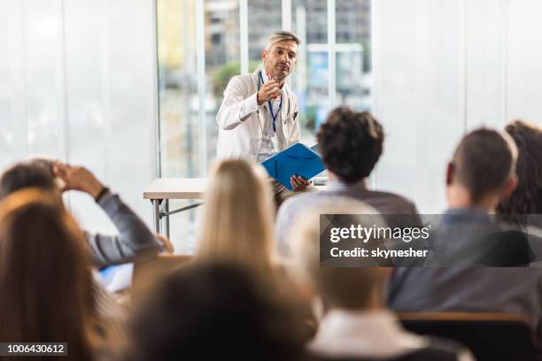 mid adult doctor teaching on a seminar in a board room. - palestra imagens e fotografias de stock