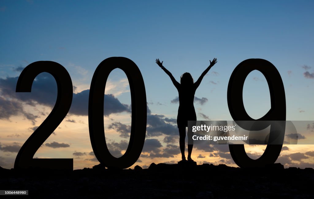 Kvinna njuter på kullen och 2019 år medan firar nyår