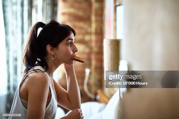 young woman biting piece of toast and checking herself in mirror - instant stock pictures, royalty-free photos & images