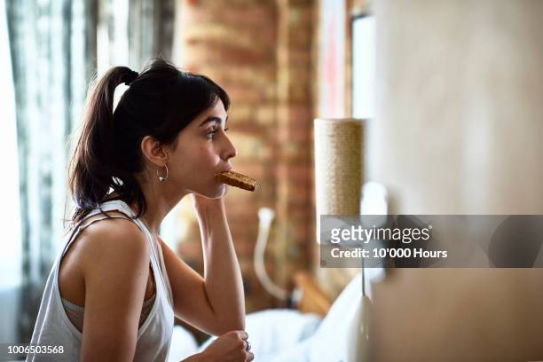 young woman biting piece of toast and checking herself in mirror - breakfast woman bildbanksfoton och bilder