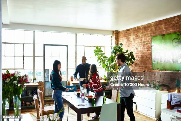 flat mates getting ready for dinner in modern loft apartment - housemates stockfoto's en -beelden