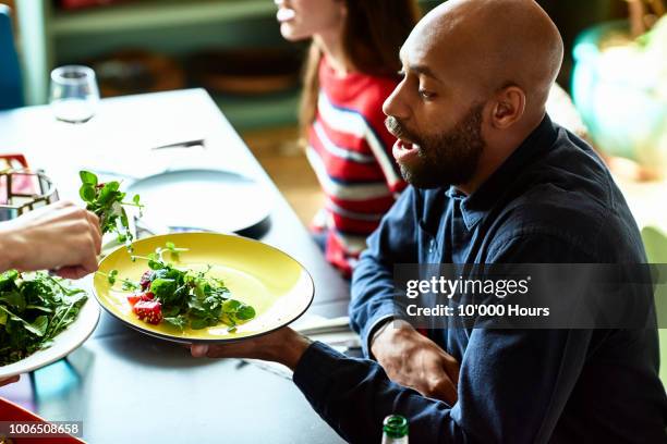 Mid adult man at dinner party holding plate and being served salad