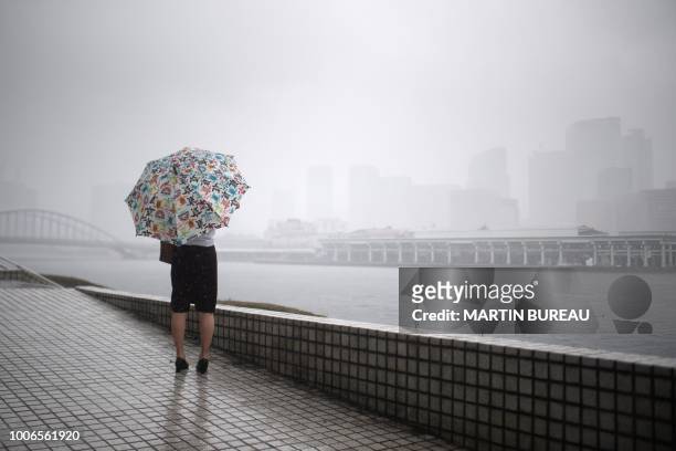 Woman protects herself from the rain with an umbrella in Tokyo on July 28 as the country braces for Typhoon Jongdari. - A powerful typhoon hurtled...