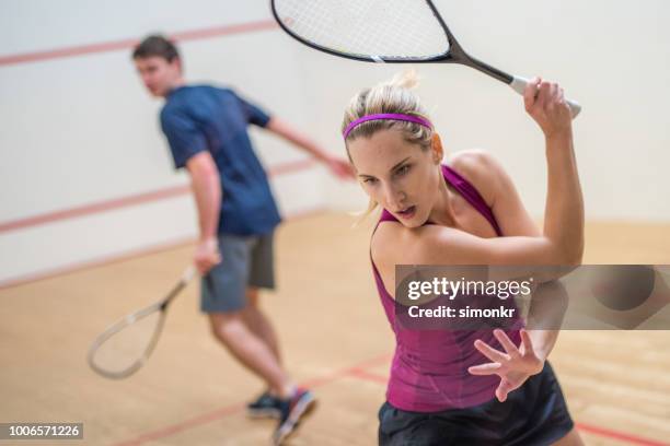 junger mann und frau beim squash-spiel - squash racquet stock-fotos und bilder