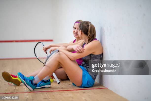 dos amigas sentada en la cancha de squash después de juego y chat - squash racquet fotografías e imágenes de stock