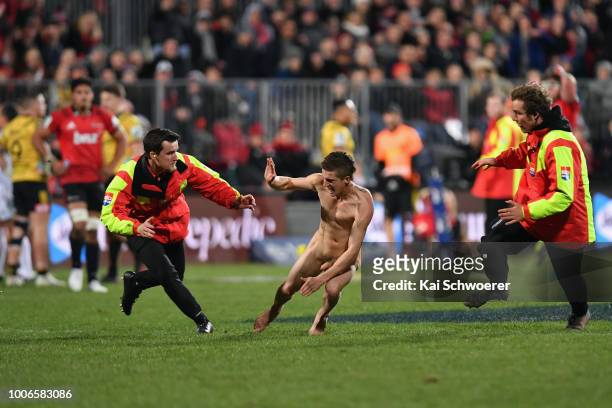Pitch invader is tackled by security guards during the Super Rugby Semi Final match between the Crusaders and the Hurricanes at AMI Stadium on July...
