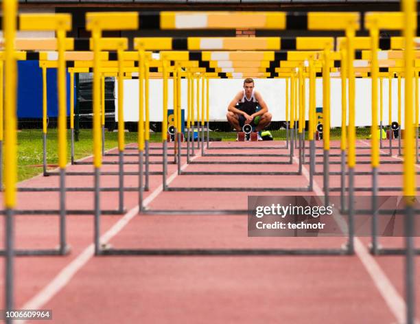 vista frontal de la joven atleta a través de los obstáculos - hurdle race fotografías e imágenes de stock