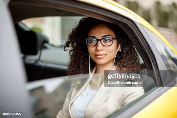 businesswoman listening to music while commuting to work by taxi - music from the motor city stock pictures, royalty-free photos & images