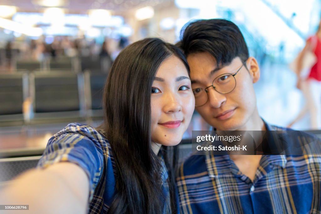 Young Asian couple taking selfie pictures in airport