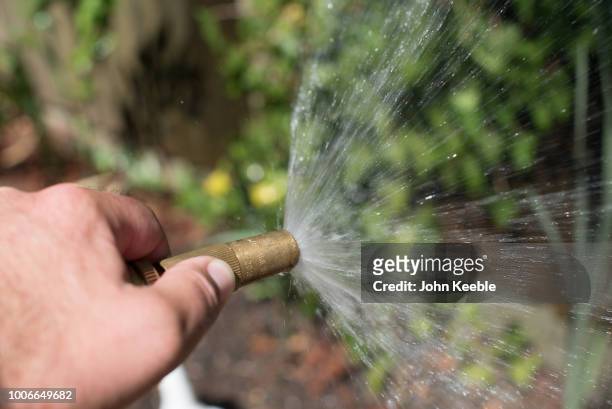 Water sprays from a hosepipe as a man waters a garden on July 24, 2018 in Leigh On Sea, England. Seven million residents in the north west of England...