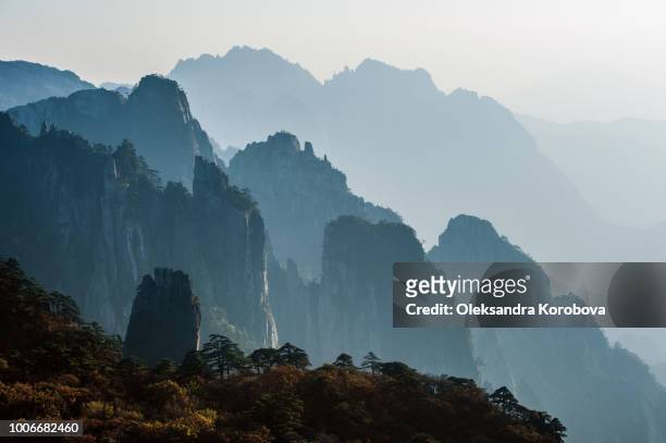 sunset in the huangshan mountain range - anhui province, china. evening sun lights the cliffs below and observation deck. - china east asia stock pictures, royalty-free photos & images