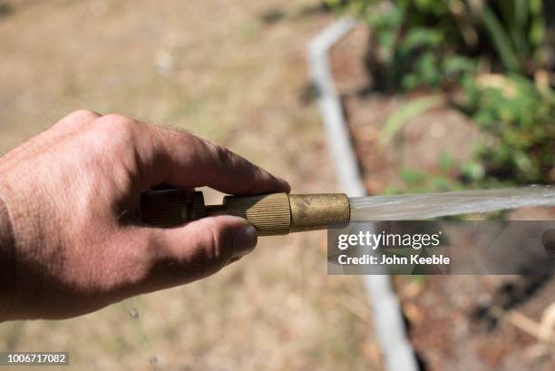 Water sprays from a hosepipe as a man waters a garden on July 24, 2018 in Leigh On Sea, England. Seven million residents in the north west of England...