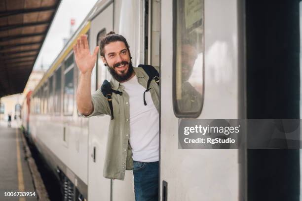 young man smiling and waving his hand from the train - train leaving stock pictures, royalty-free photos & images