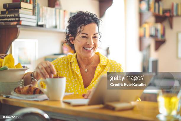mature woman working at home - breakfast lifestyle female imagens e fotografias de stock