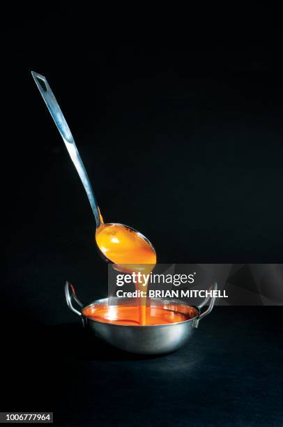 tomato soup being poured into a metal soup bowl with a ladle. - louche photos et images de collection