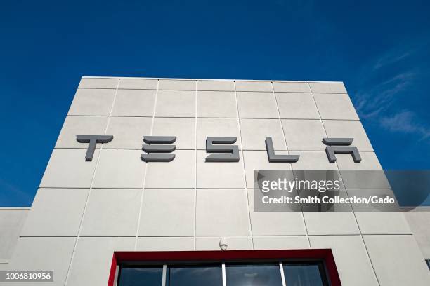 Low-angle view of the facade of Tesla Motors dealership with logo and sign in Pleasanton, California, July 23, 2018.