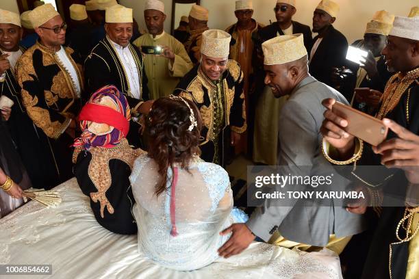 Guests take turns to be photographed with the newly weds during a traditional wedding ceremony at the home of the bride in Moroni July 28 capital of...