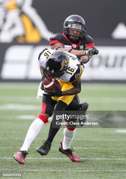 Loucheiz Purifoy of the Ottawa Redblacks tackles Brandon Banks of the Hamilton Tiger-Cats in a CFL game at Tim Hortons Field on July 28, 2018 in...