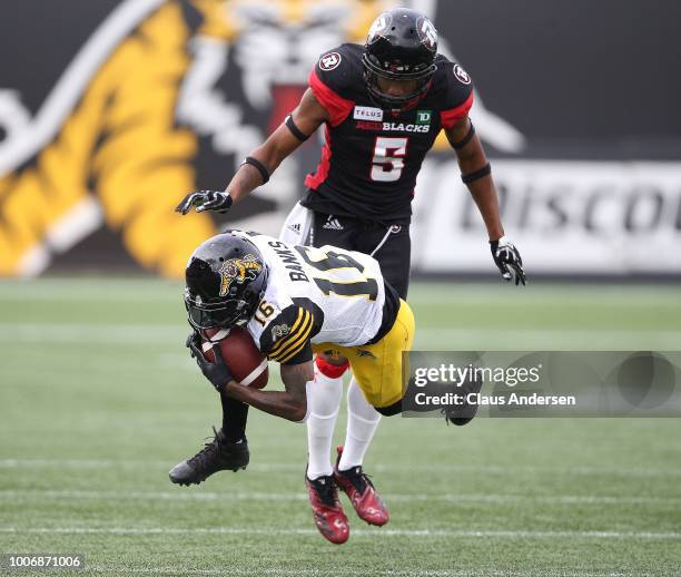 Loucheiz Purifoy of the Ottawa Redblacks tackles Brandon Banks of the Hamilton Tiger-Cats in a CFL game at Tim Hortons Field on July 28, 2018 in...