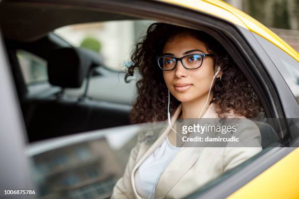 femme d’affaires écouter de la musique pendant le trajet en taxi - in ear headphones photos et images de collection