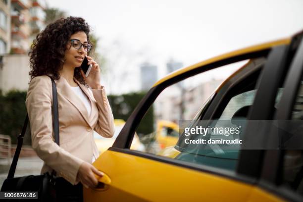 タクシーに乗るビジネスウーマン - yellow taxi ストックフォトと画像