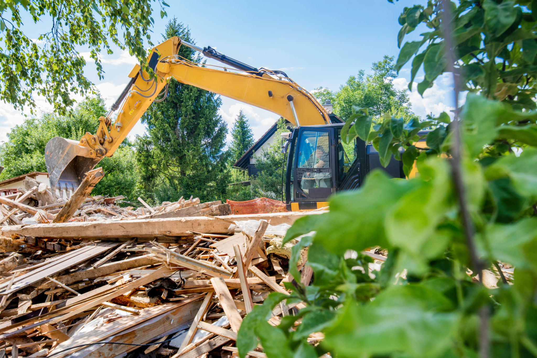 Excavator clearing rubble after demolishing a house Excavator clearing rubble after demolishing a house