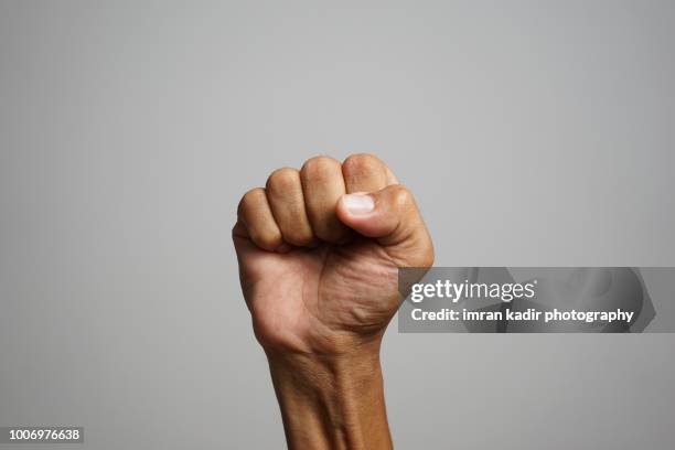 asian skin showing fists in right hand with grey background - revolution fist stock pictures, royalty-free photos & images