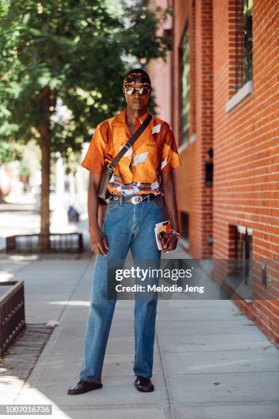 Model Aly Ndiaye wears a headband, sunglasses, orange print shirt, blue jeans, and leather loafers during New York Fashion Week Men’s Spring/Summer...