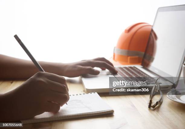 close-up hand of male architect drawing blueprint on work space wooden table in office - cad drawing stock pictures, royalty-free photos & images