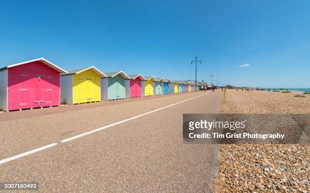 a row of multi-coloured beach huts - uferpromenade stock-fotos und bilder