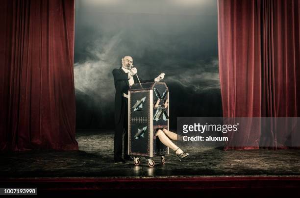 magician inserting swords in box occupied by female assistant - magician stock pictures, royalty-free photos & images