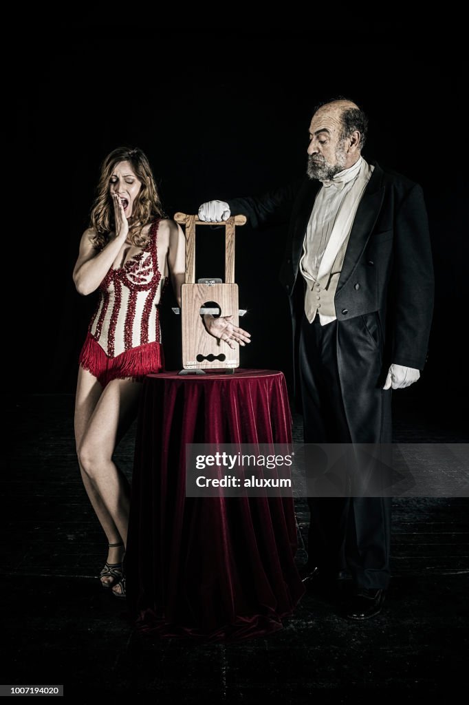 Magician Doing Guillotine Trick With Assistant On Stage High Res Stock magician-doing-guillotine-trick-with-assistant-on-stage-high-res-stock