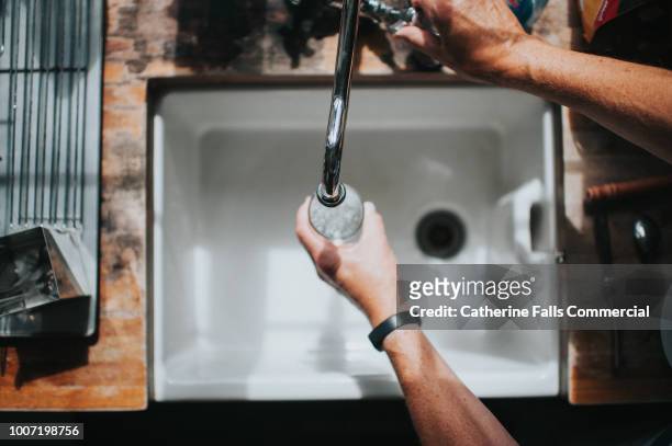 belfast sink with running water tap - waterkraan stockfoto's en -beelden